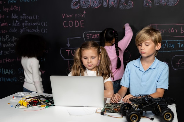 Smart girl in white bib learning robotics technology using laptop erudition