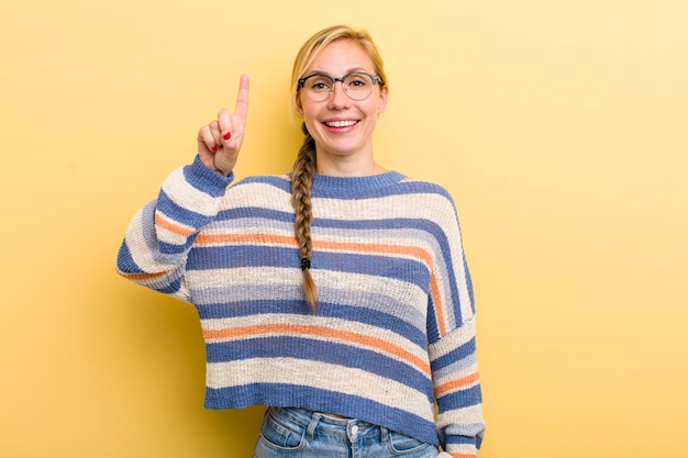 Smiling cheerfully and happily pointing upwards with one hand to copy space