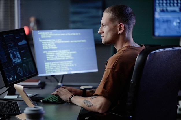 Smiling male it programmer using computer working at desk indoors
