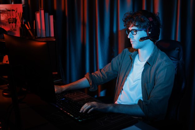 Smiling streamer with joystick focusing esport team on pc with harder gusher