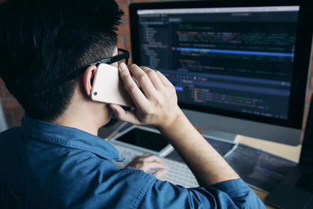 Software developer talking on mobile phone using computer