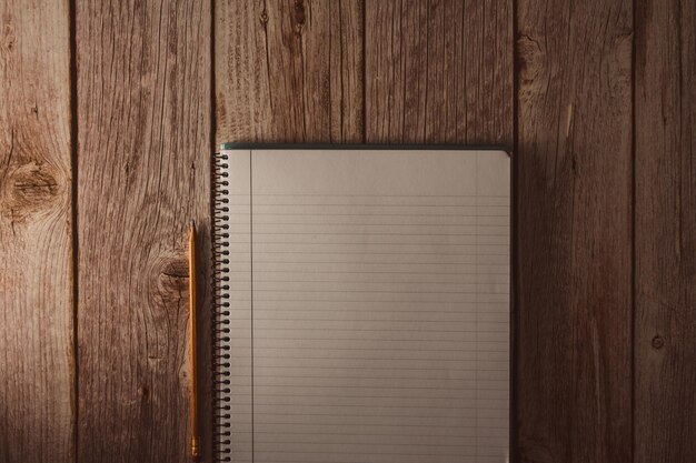 spiral notebook in white with lines and pencil on wooden background top view copy space