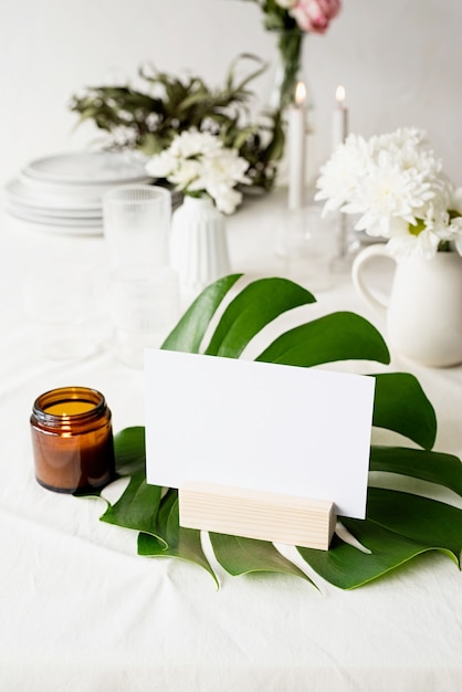 Stand for booklets with white paper, wooden tent card on monstera leaf on restaurant table