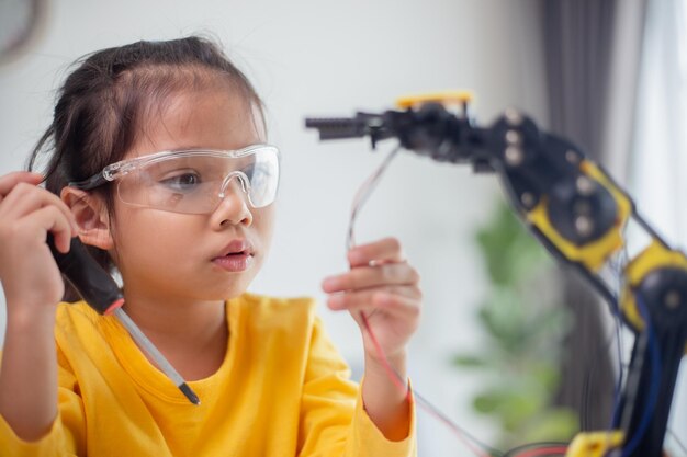 STEM education concept Asian students learn at home by coding robot arms in STEM mathematics engineering science technology computer code in robotics for kids concepts