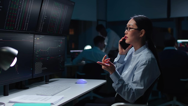 Stock market trader buying and selling over the phone looking at computer screens