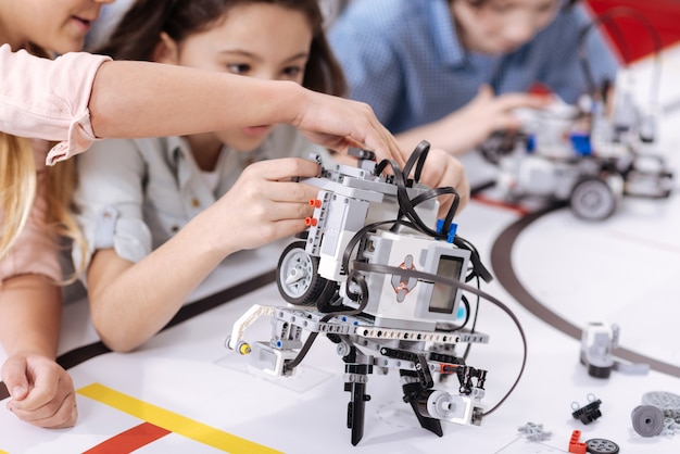 Streamlined robot. Modern futuristic electronic robot standing in front of the children on the table and performing functions while demonstrating tech progress