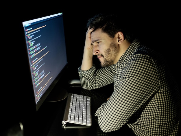Stressad mjukvaruutvecklare med dator på hemmakontoret