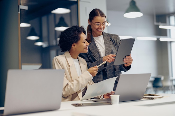 Foto stylish female executives managers discussing financial accounting papers and using digital tablet