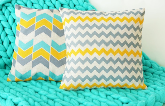 Stylish pillows with turquoise plaid on white couch