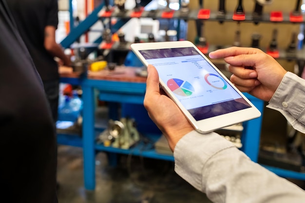 supervisor explaining a pie chart to team over digital tablet in factory