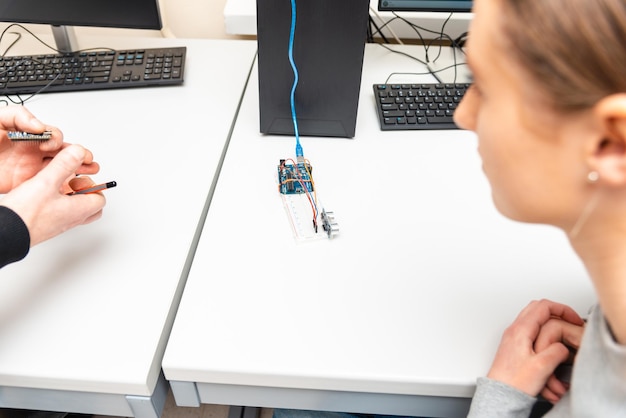 Teacher helping his teen student with diy robot on stem education classStudent In After School Computer Coding Class Building And Learning To Program Robot VehicleArduino Ultrasonic installation