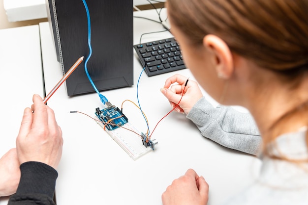 Teacher helping his teen student with diy robot on stem education classStudent In After School Computer Coding Class Building And Learning To Program Robot VehicleArduino Ultrasonic installation