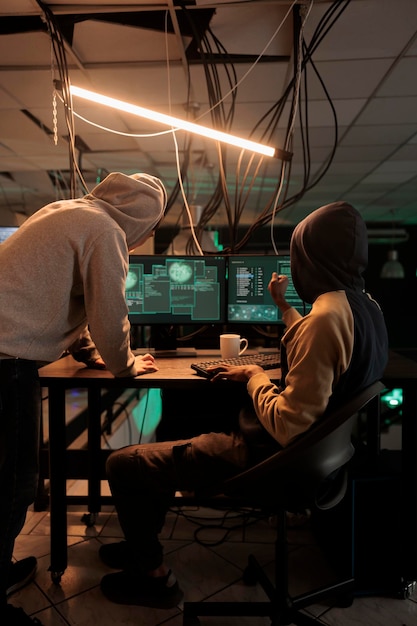 Team of cybercriminals trying to crack firewall encryption, using virus to hack government system at night. Young men breaking into database to steal passwords and sensitive information.