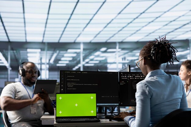 Team of programmers in server farm using green screen laptop