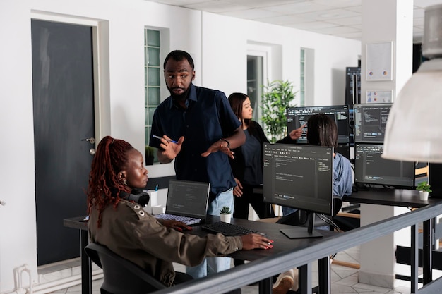 Team of programmers typing machine learning app code on programming computer, sitting at desk in big data office. Web developers working on database system with html script in it security agency.