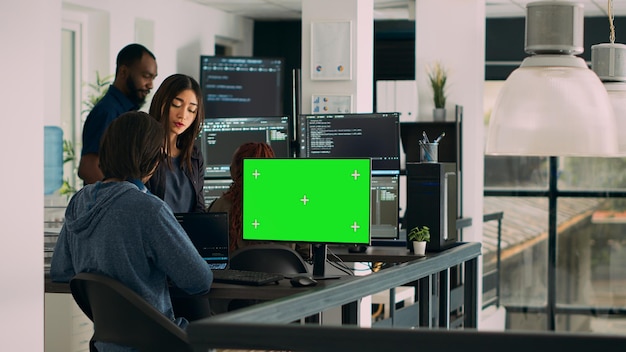Team of programmers working on source code with greenscreen monitor in cloud computing office. App developers checking isolated chromakey display with copyspace and html script. Tripod shot.