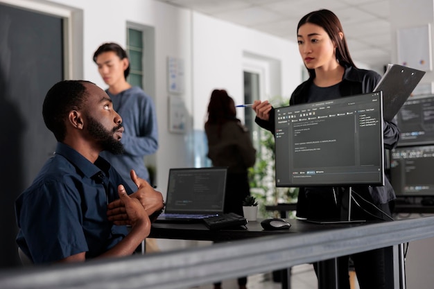 Team of system engineer working on terminal window with html script and writing server code, sitting in it agency. App developer programming user interface in busy developing office room.