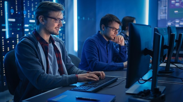 Team of Young IT Programers Working on Desktop Computers in Data Center System Control Room Displays Show Concept Software Development Code Writing Database Architecture Technical Department