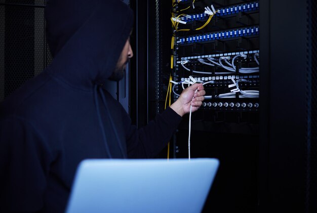 Thief programming and hacker stealing software website data and information on server on a laptop Connection criminal and man hacking into a network for hardware coding and cyber crime at night
