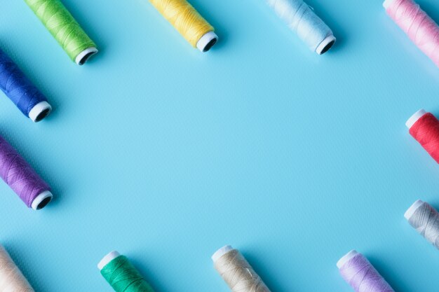 Thread tube colorful on blue background top view and copy space