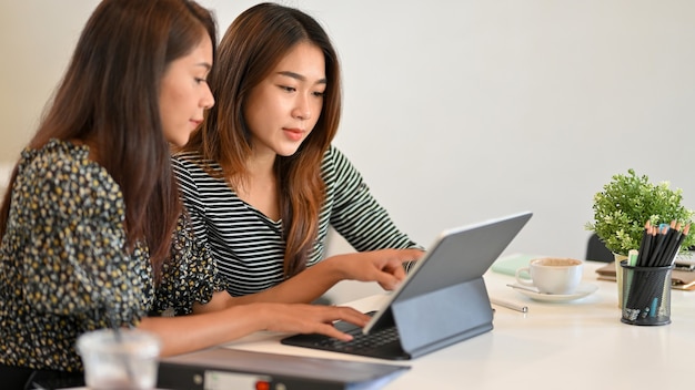 Two business female worker use tablet to discuss business strategy together at office businesswomen