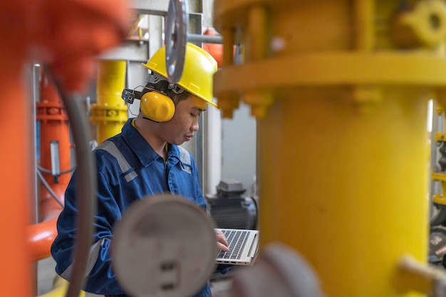 Underhållstekniker på ett värmeverk. Petrokemiska arbetare övervakar driften av gas- och oljeledningar i fabriken. Ingenjörer sätter på hörselskydd i ett rum med många rör