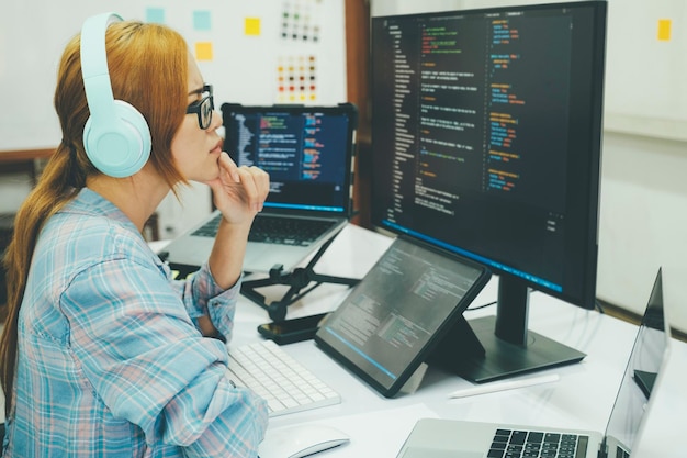 Ung kvinde dækker sit ansigt på grund af arbejdsrelateret stress ved kodning og programmering af software