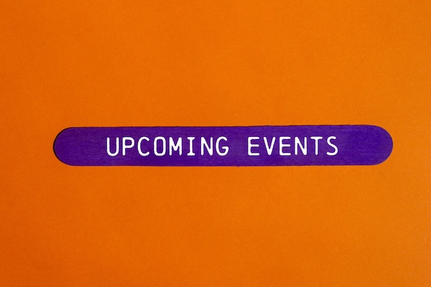 Upcoming events message written on purple wooden stick on orange background Conceptual upcoming events symbol Copy space