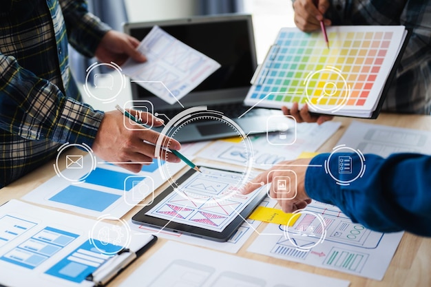 UX developer and ui designer brainstorming about mobile app interface wireframe design with customer breif and color code at office with virtual iconxA