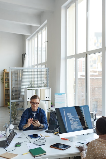 Vertical portrait of modern IT developers using computers for code programming while working on VR software in office, copy space