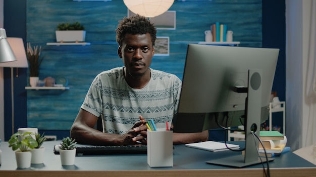 Voksen af afrikansk etnicitet, der bruger computer til fjernarbejde