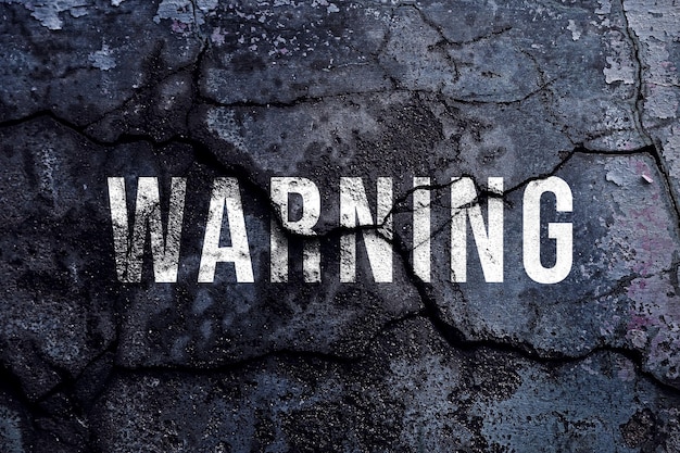 warning text written with broken cement wall warning word on street