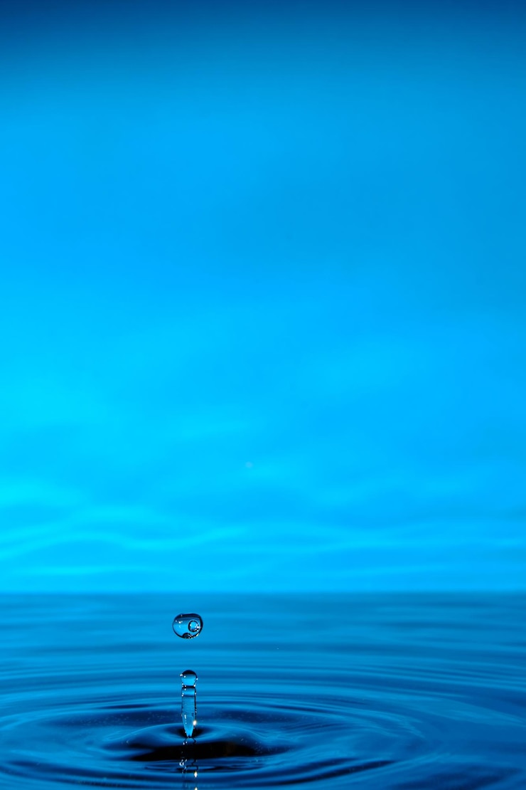 Bild water splashes after raindrop falls.blue abstract background with splash of drop of water.
