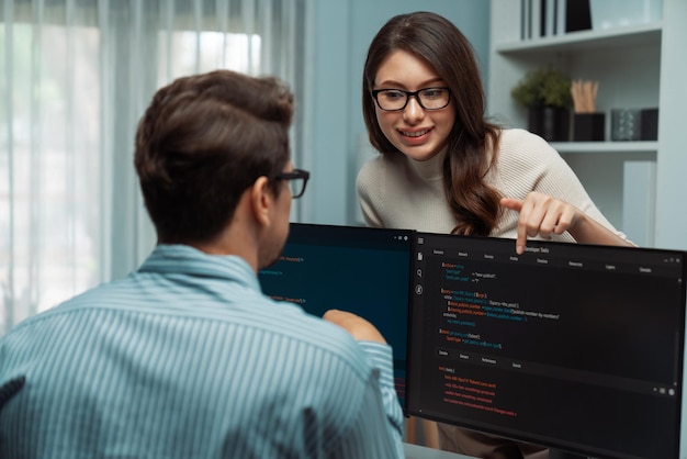 Woman standing opposite to man programmer working on desk to discuss postulate