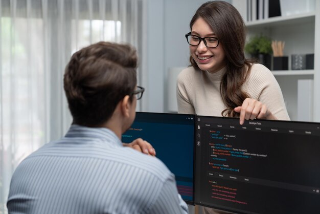 Woman standing opposite to man programmer working on desk to discuss Postulate