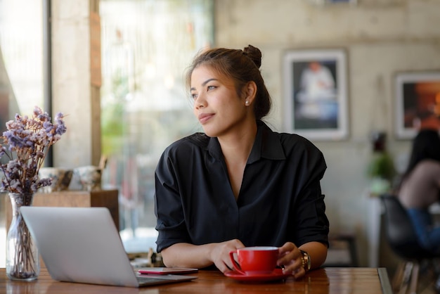 Woman with laptop sitting at table in restaurant