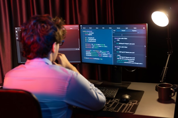 Working IT developer concentrating online software development information on surrounded by coding application pc screens creating program for firmware on website at neon modern office home Gusher