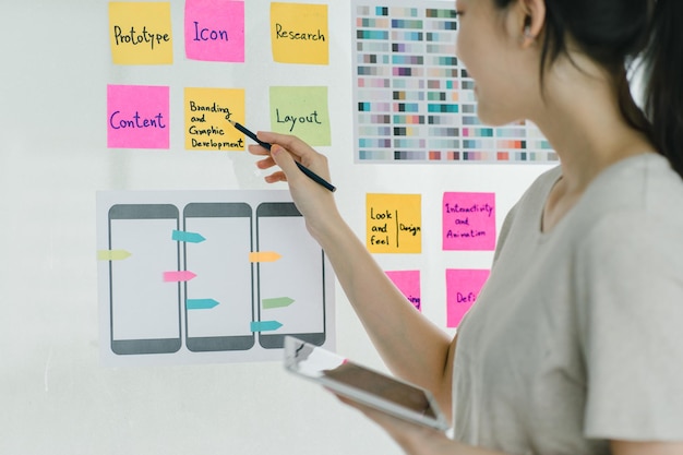 Young asian designer brainstorming app interface with colorful sticky notes