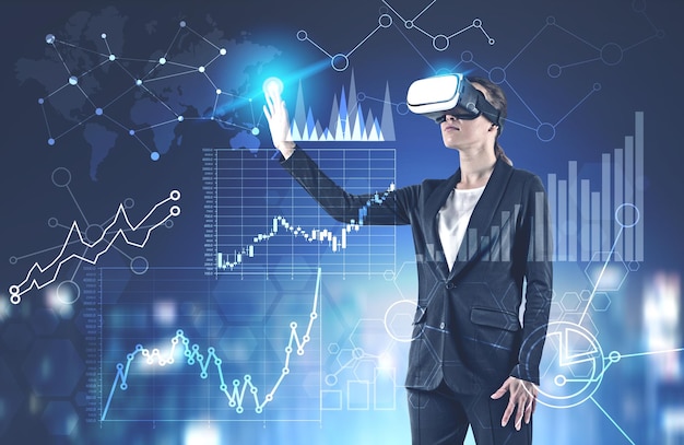 Young businesswoman in black suit and VR glasses working with interactive business infographics interface. Toned image double exposure