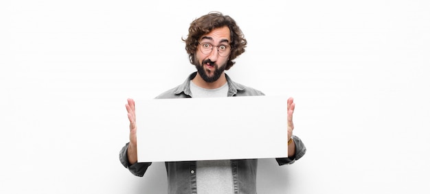 Young crazy cool man holding a placard on white wall