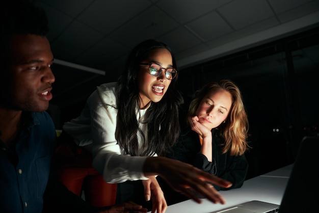 Young female businesswoman discussing the project with her two colleagues in dark office till late night