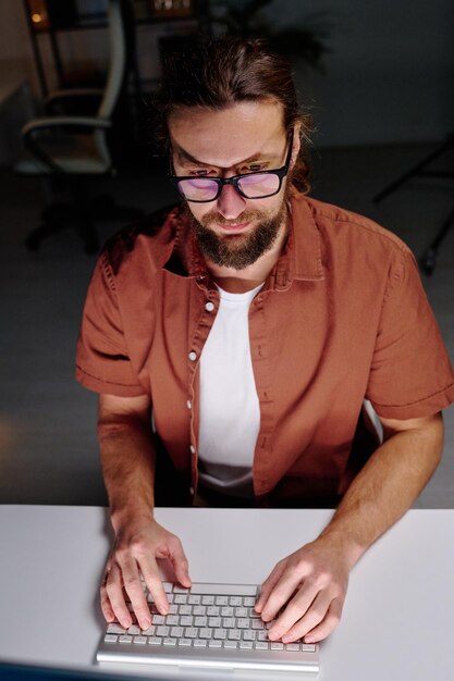 Young male programmer in eyeglasses looking at computer screen