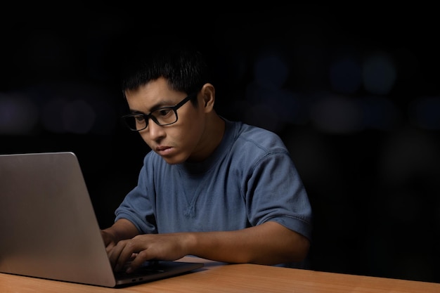 Young man with eye glasses browsing at his computer laptop at home, work from home concept.