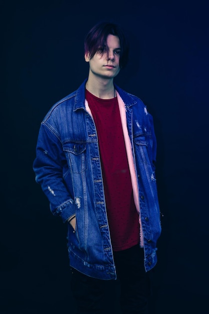 young man with pink and black hair in red shirt on a dark blue background