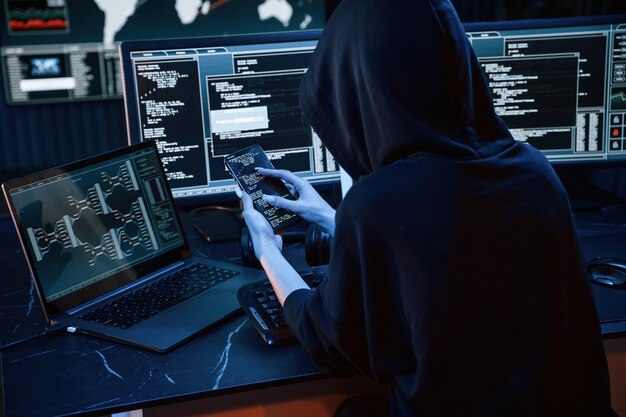Young professional female hacker is indoors by computer with lot of information on displays