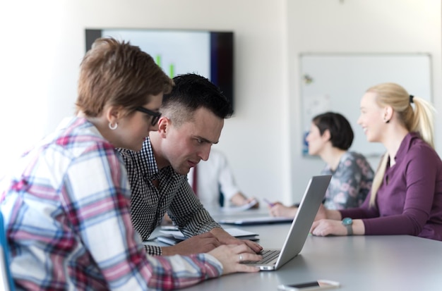 young startup  business people, couple working on laptop computer,  businesspeople group on meeting in background at office interior