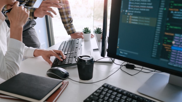 Young startup Programmers Sitting At Desks Working On Computers screen for Developing programming and coding to find solution to problem on New Application.