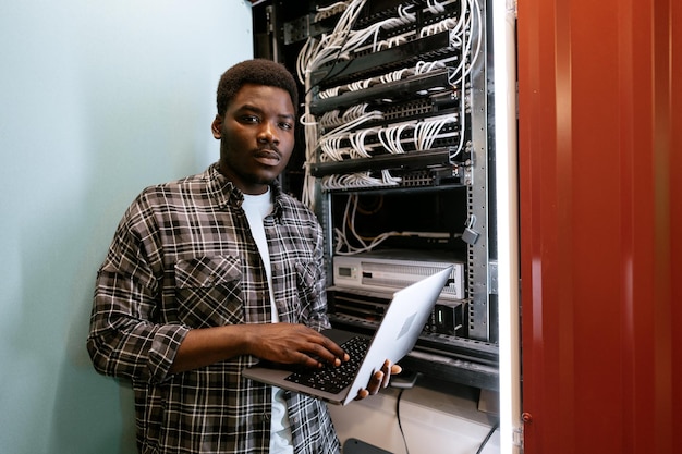 Young technician working on network server in data center during afternoon