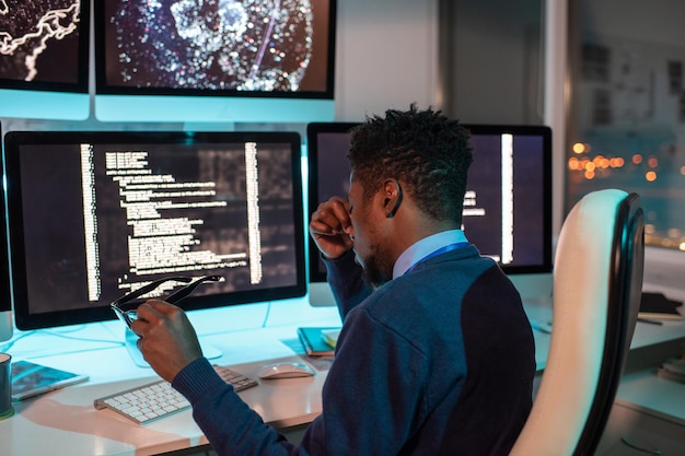 Young tired african businessman sitting in front of computer monitor