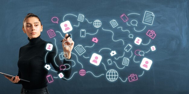 Young woman drawing social media icons on a dark background illustrating modern communication and networking concepts
